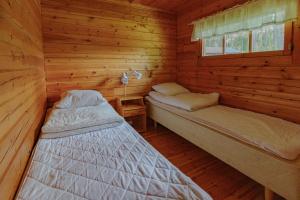 クオピオにあるRauhalahti Holiday Cottagesのログキャビン内のベッドルーム1室(ベッド2台付)