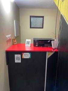 una oficina con un mostrador rojo y una nevera negra en OYO Hotel Munroe Homestay en Kollam