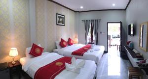 Le KhounSok Boutique Hotel في لوانغ برابانغ: سريرين في غرفة الفندق باللون الأحمر والأبيض