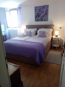 a bedroom with a large bed with purple sheets and pillows at Rooms Serafin-Lavanda in Motovun