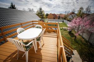una terraza de madera con una mesa y sillas blancas en Olivia Apartment House en Balatonboglár