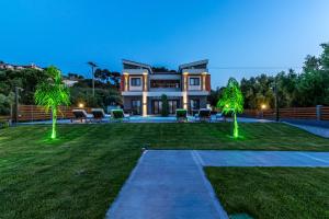 una casa con dos palmeras en el patio en Assos Luxury Villas en Pefkohori