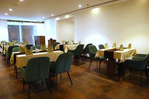 une salle à manger avec des tables et des chaises vertes dans l'établissement Hotel Seven Lights, à Ernakulam