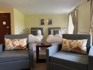 Habitación con 2 camas, sofá y silla en Lovelady Shield Country House Hotel, en Alston