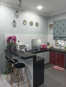 a kitchen with a counter and two bar stools at Damai D Homestay in Kangar