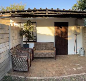 a patio with two wicker chairs and a bench at Jan Bantjies Inn in Pretoria