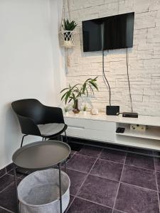 ein Wohnzimmer mit 2 Stühlen und einem TV an der Wand in der Unterkunft Mala kuća ispod borova in Primošten