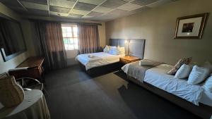 een hotelkamer met 2 bedden en een raam bij Mountainview Inn in Harrismith