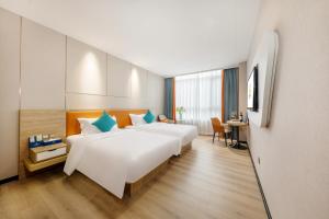 um quarto de hotel com duas camas e uma secretária em Qianhai Holiday Hotel em Bao'an