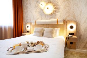 a tray of coffee and tea on a bed at Kyriad Prestige Hotel Clermont-Ferrand in Clermont-Ferrand