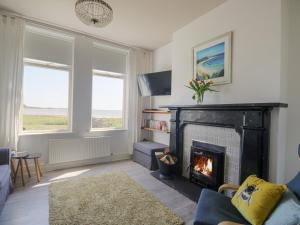 a living room with a fireplace and a couch at Pow-Wow Shore Cottage in Annan