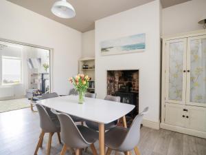 a dining room with a white table and chairs at Pow-Wow Shore Cottage in Annan