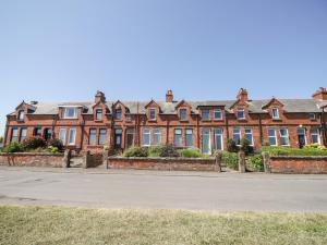 a large brick building on the side of a street at Pow-Wow Shore Cottage in Annan
