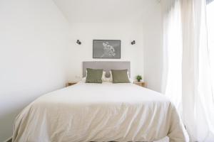a white bedroom with a large white bed with green pillows at Moott Homes Suites Casa de los Leones APTO 2 in Almería