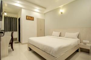a bedroom with a large white bed and a desk at Hotel Metropolitan in Jaipur