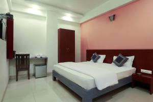a bedroom with a large bed with a pink wall at Hotel Metropolitan in Jaipur