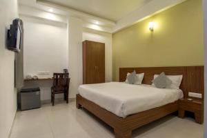 a bedroom with a bed and a desk and a television at Hotel Metropolitan in Jaipur