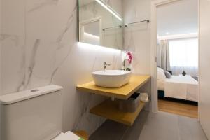 a white bathroom with a sink and a bedroom at Minimal apartment in Plaka in Athens +14 photos