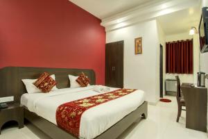 1 dormitorio con 1 cama con pared roja en Hotel Metropolitan, en Jaipur