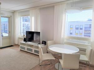 sala de estar blanca con mesa y TV en Saunallinen kaksio ilmastoinnilla ja autopaikalla! en Oulu