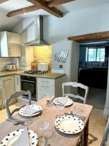 a kitchen with a wooden table with plates and wine glasses at Cotswold Cottage- Central Witney in Witney