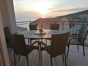 a dining table and chairs on a balcony with the sunset at Apartman Vesa in Dolac