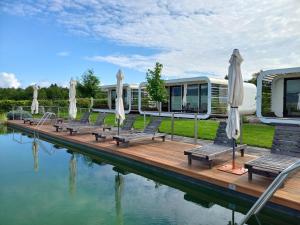 a group of chairs and umbrellas on a dock next to water at Glamping Maleric with Natural Pool in Dragatuš