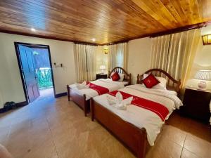 um quarto com 2 camas e almofadas vermelhas em Villa Phathana Royal View Hotel em Luang Prabang