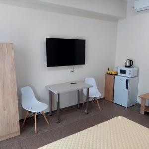 Cette chambre dispose d'une table, de deux chaises et d'une télévision. dans l'établissement Fermelor Residence, à Piatra Neamţ