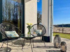 a patio with two chairs and a table with a vase of flowers at Luxus-Ferienhaus CASA LUNA in Göhren-Lebbin