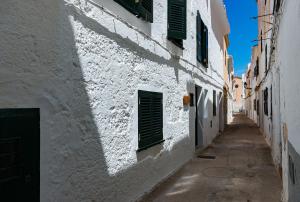 an alley with white buildings and green shutters at Samarés in Ciutadella