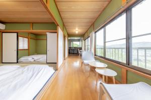 a room with a bed and chairs and windows at 天然温泉&絶景露天風呂付き貸切宿のんびり一非日常空間を愉しむ一10人でも広々 in Izu