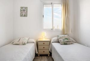 2 aparte bedden in een kamer met een raam bij Casa María in Conil de la Frontera