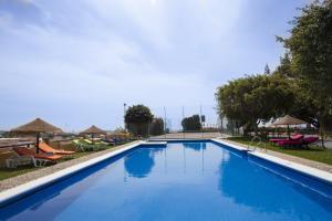 una gran piscina azul con sillas y sombrillas en Cortijo Amaya, en Torrox Costa