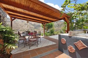 a patio with a table and chairs under a wooden pergola at Finca Los Tableros in Hermigua