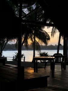 a table and benches on a beach with the ocean at Mambo’s hotel Arugam Bay in Pottuvil