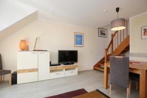 a living room with a television and a desk with a table at Papillon Wohnung 18-6 in Boltenhagen