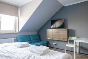 - une chambre avec un lit et une télévision sur un mur bleu dans l'établissement Penzion Janota Perná, à Perná