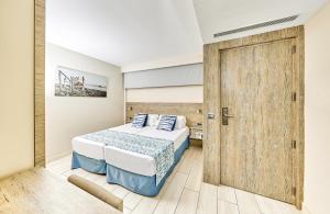 1 dormitorio con 1 cama y puerta de madera en Leonardo Royal Hotel Mallorca Palmanova Bay en Palmanova