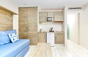 a living room with a blue couch and a kitchen at Leonardo Royal Hotel Mallorca Palmanova Bay in Palmanova