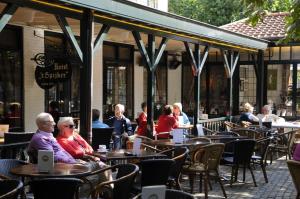 un grupo de personas sentadas en las mesas fuera de un restaurante en Hotel 't Spijker, en Beek