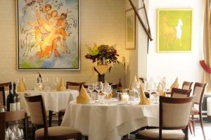 a dining room with white tables and chairs and a painting at Hotel 't Spijker in Beek