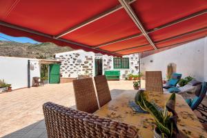 a patio with a table and chairs under a red umbrella at Rosa del Negro in Alojera