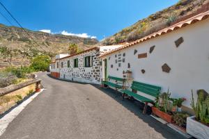 a row of white buildings with green benches on a road at Rosa del Negro in Alojera