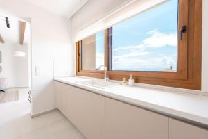 baño con lavabo y ventana en Tris, en Nikiti