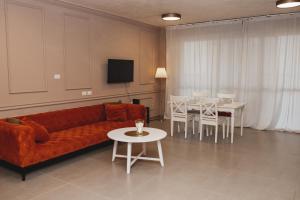 ein Wohnzimmer mit einem Sofa, einem Tisch und Stühlen in der Unterkunft Стильные апартаменты Dotan in Netanya