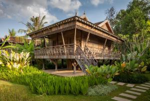 a wooden house with a deck in a garden at Sala Lodges in Siem Reap