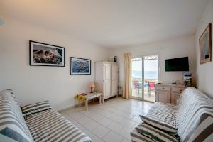 sala de estar con sofá y TV en Romarin - Appt pour 4 voyageurs avec splendide vue mer, en Le Lavandou