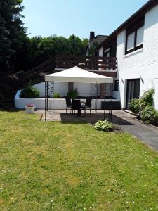 um pátio com uma mesa e um guarda-chuva branco em Eifeloase Sophia em Nettersheim