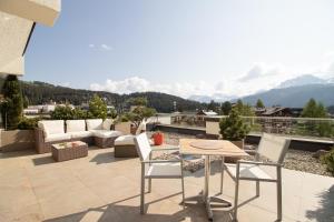 eine Terrasse mit einem Tisch und Stühlen auf dem Balkon in der Unterkunft Galerie Obersee 3E in Arosa